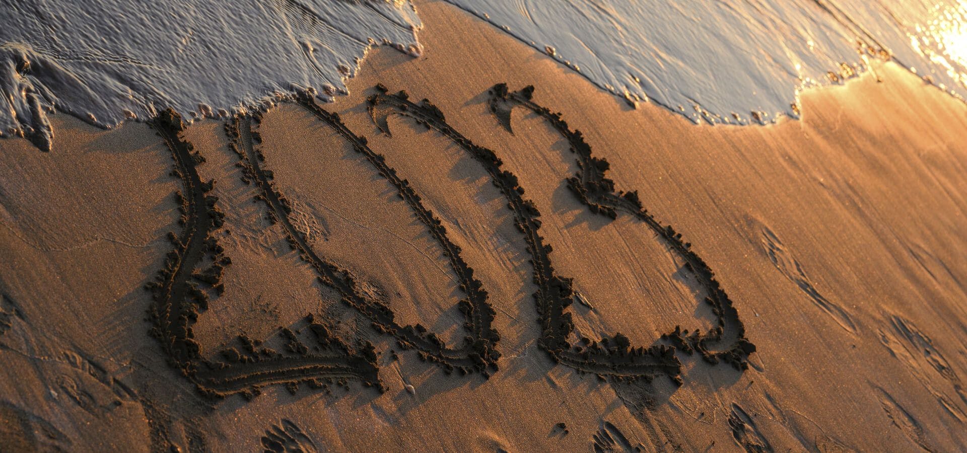 Playa con el texto 2023 escrito en la arena