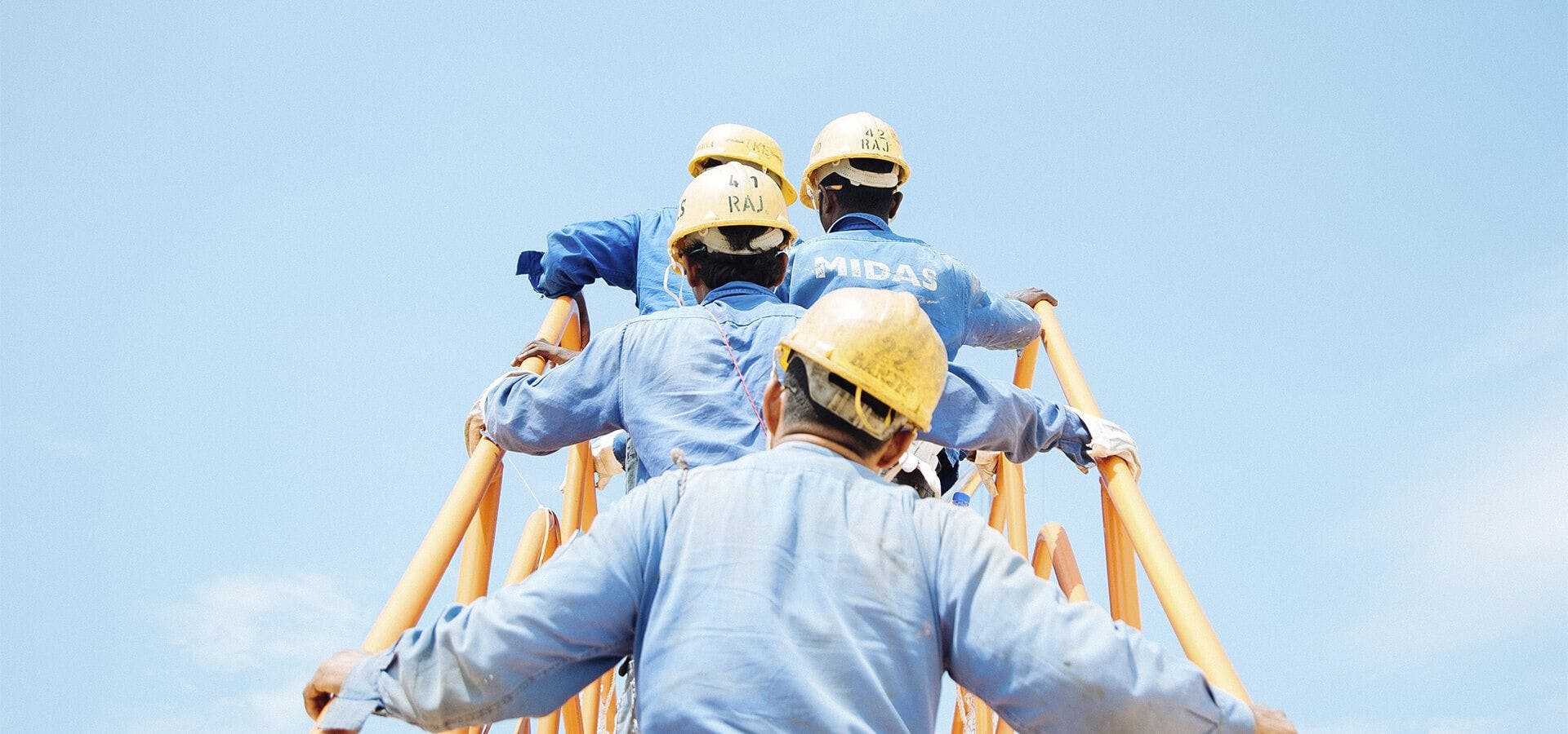 Trabajadores de la construcción subiendo por la escalera de una grúa